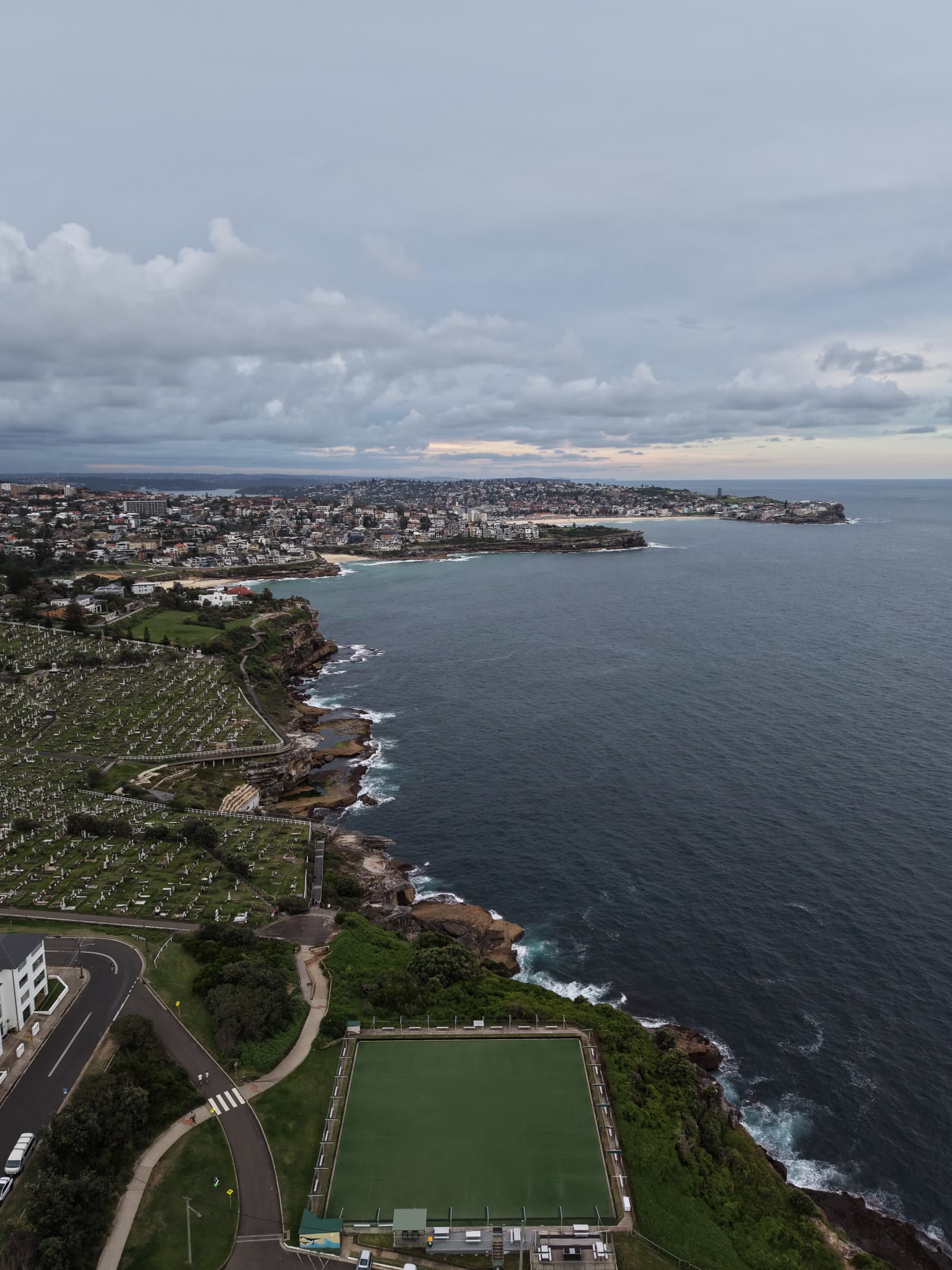 Coastline at dusk from high over the water — beaches and headlands curving away to the horizon